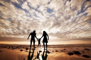 Famille profitant de leur résidence secondaire en Espagne marchant sur une plage avec un enfant