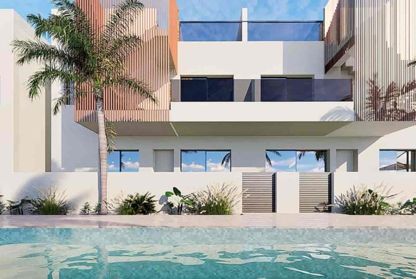 Complexe d'appartements moderne à Pilar de la Horadada, avec une façade blanche épurée, ornée de panneaux en bois. Au premier plan, une piscine cristalline entourée de palmiers et de végétation tropicale