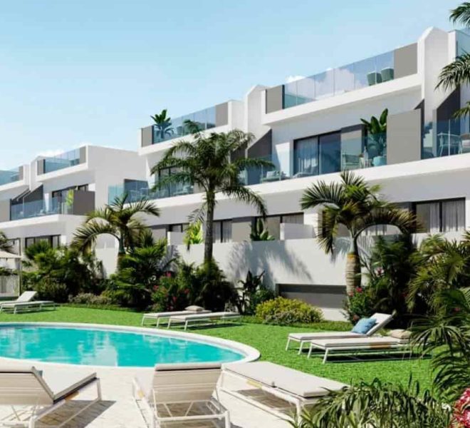 Image d’un complexe d’appartements de luxe moderne à Torrevieja avec une piscine. Le complexe est blanc et a plusieurs niveaux. La piscine est en forme de rein et a de l’eau bleue. Il y a plusieurs chaises longues et parasols autour de la piscine. Le complexe est entouré de palmiers et d’autres plantes tropicales. Le ciel est bleu et il y a quelques nuages dans le ciel.